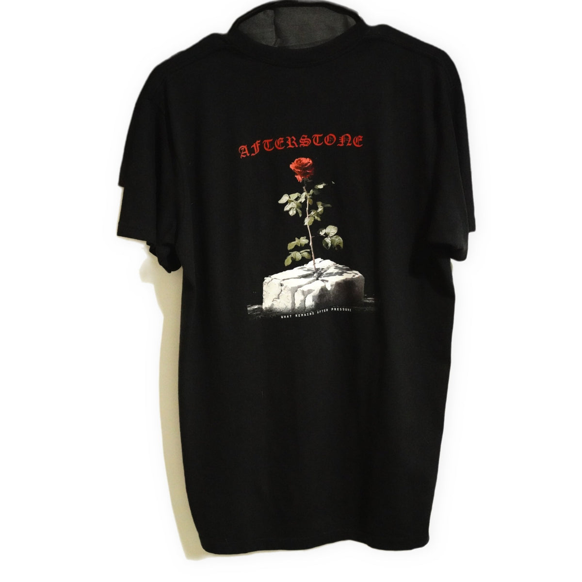 AFTERSTONE GREW ANYWAY heavyweight tee in black — rose growing out of a stone block, printed large on the back