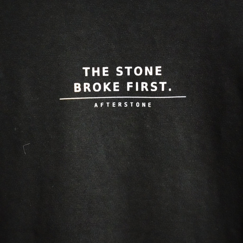 THE STONE BROKE FIRST front phrase close-up on black cotton